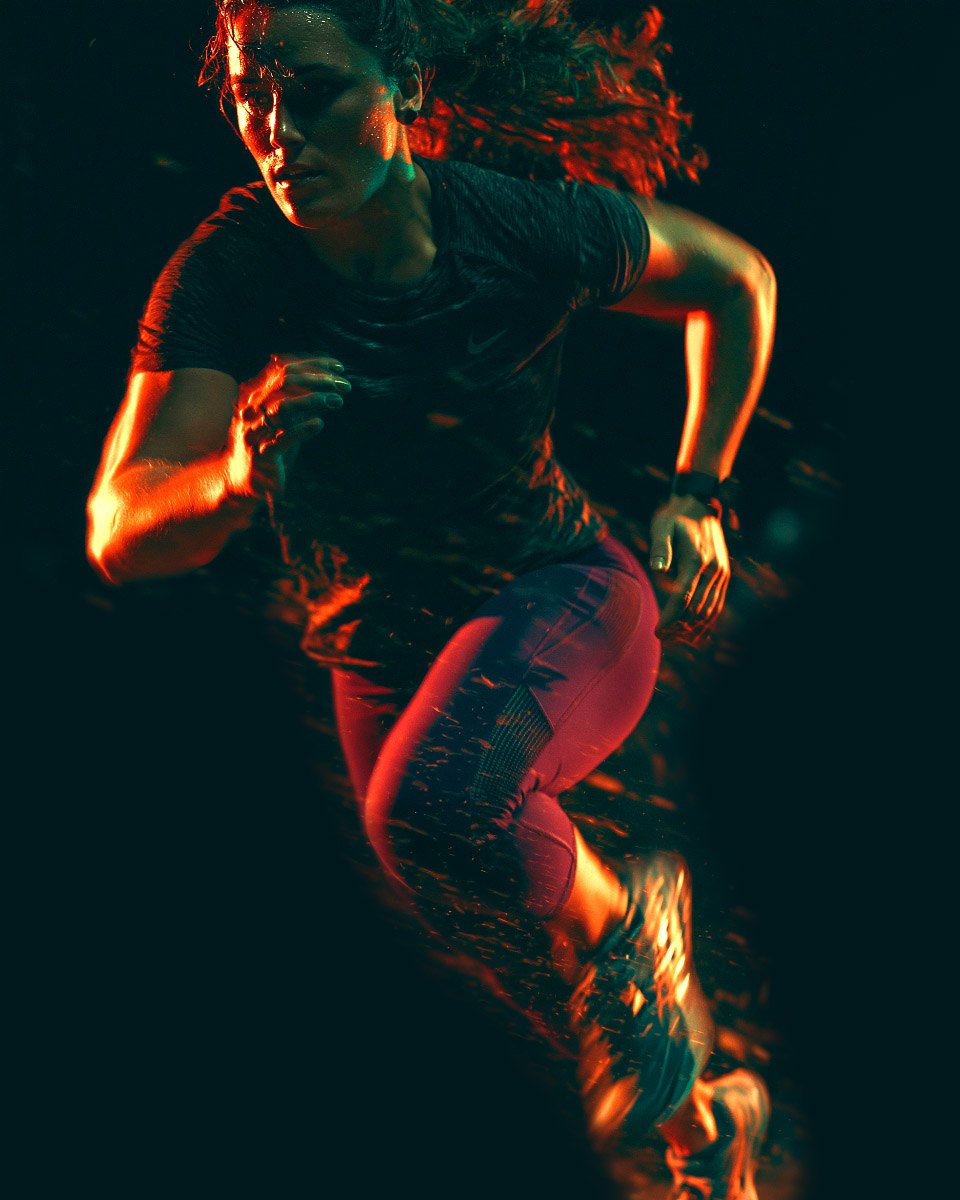 Runner in motion, lit in red and teal against the dark